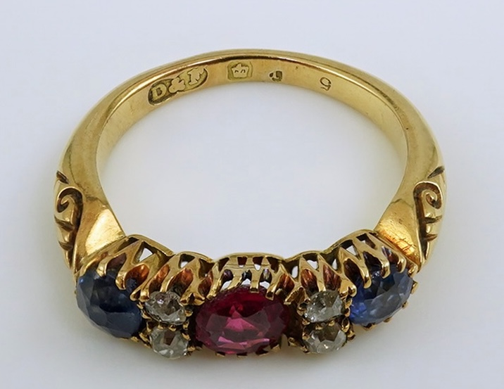 An early 20th century gold, ruby, sapphire and diamond cluster set half hoop ring